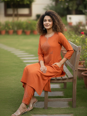 Orange kurta with mirror-detailed round neck paired with a matching trouser for a chic ethnic look.
